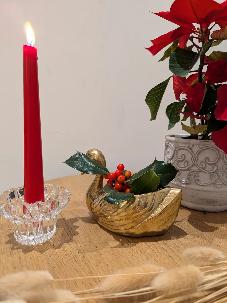Bougie rouge dans un bougeoir en verre et canard doré garni de feuillage pour une décoration de Noël vintage