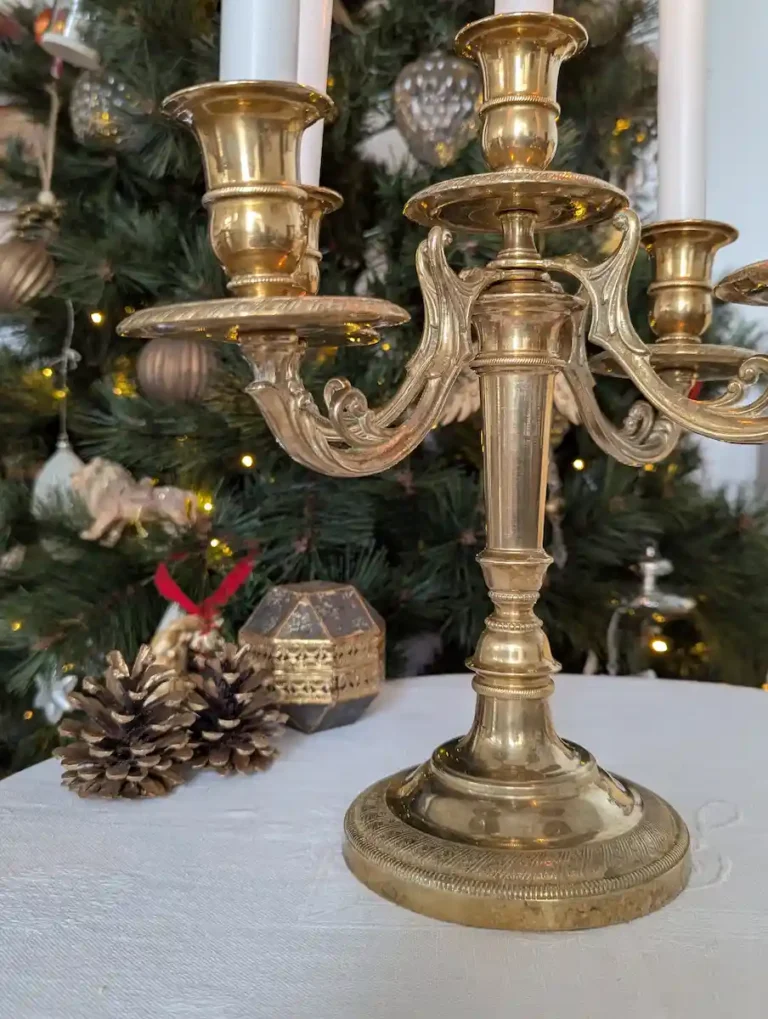 Chandelier ancien doré devant un sapin de Noël décoré de boules et de guirlandes lumineuses