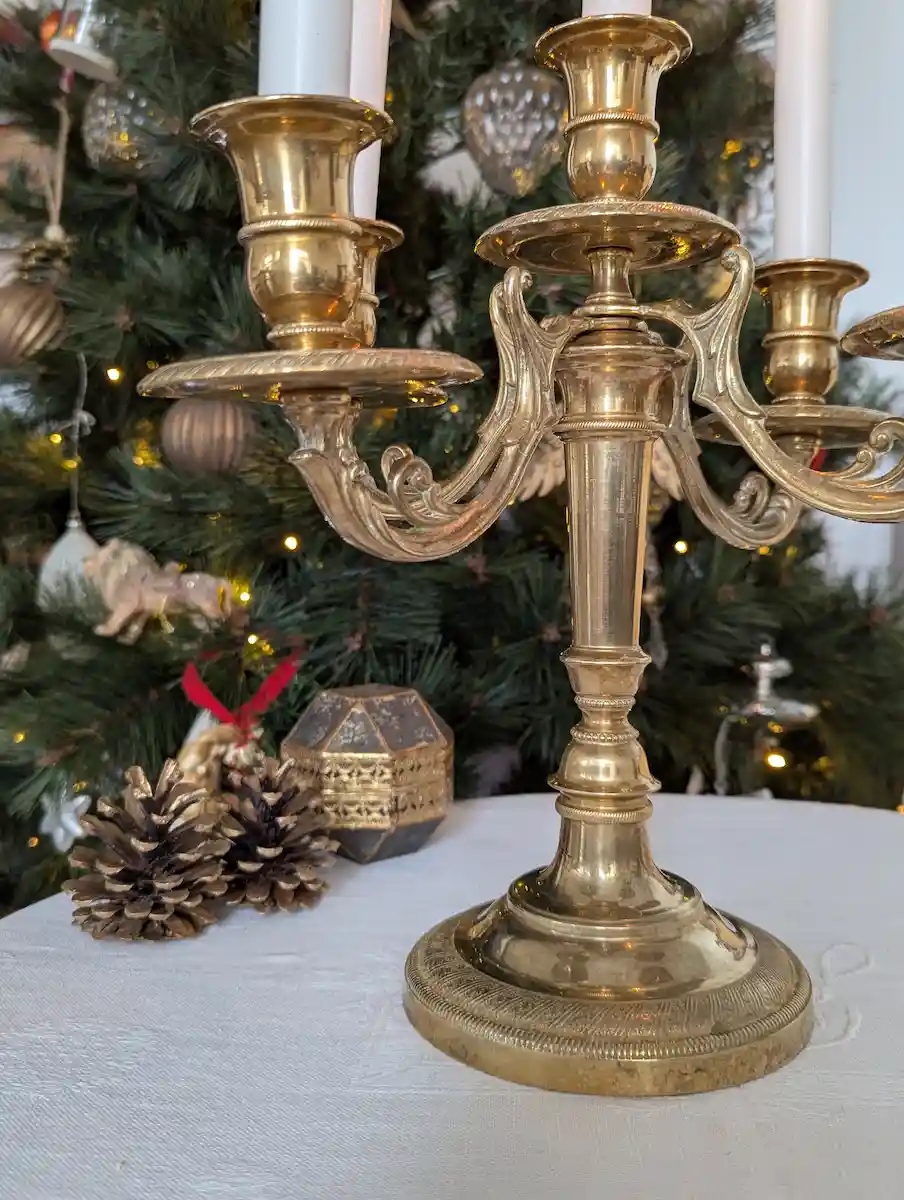 Chandelier ancien doré devant un sapin de Noël décoré de boules et de guirlandes lumineuses