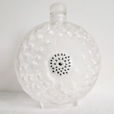 Flacon Lalique Dahlia vu de face, décor floral en cristal satiné et cœur noir, avec bouchon.