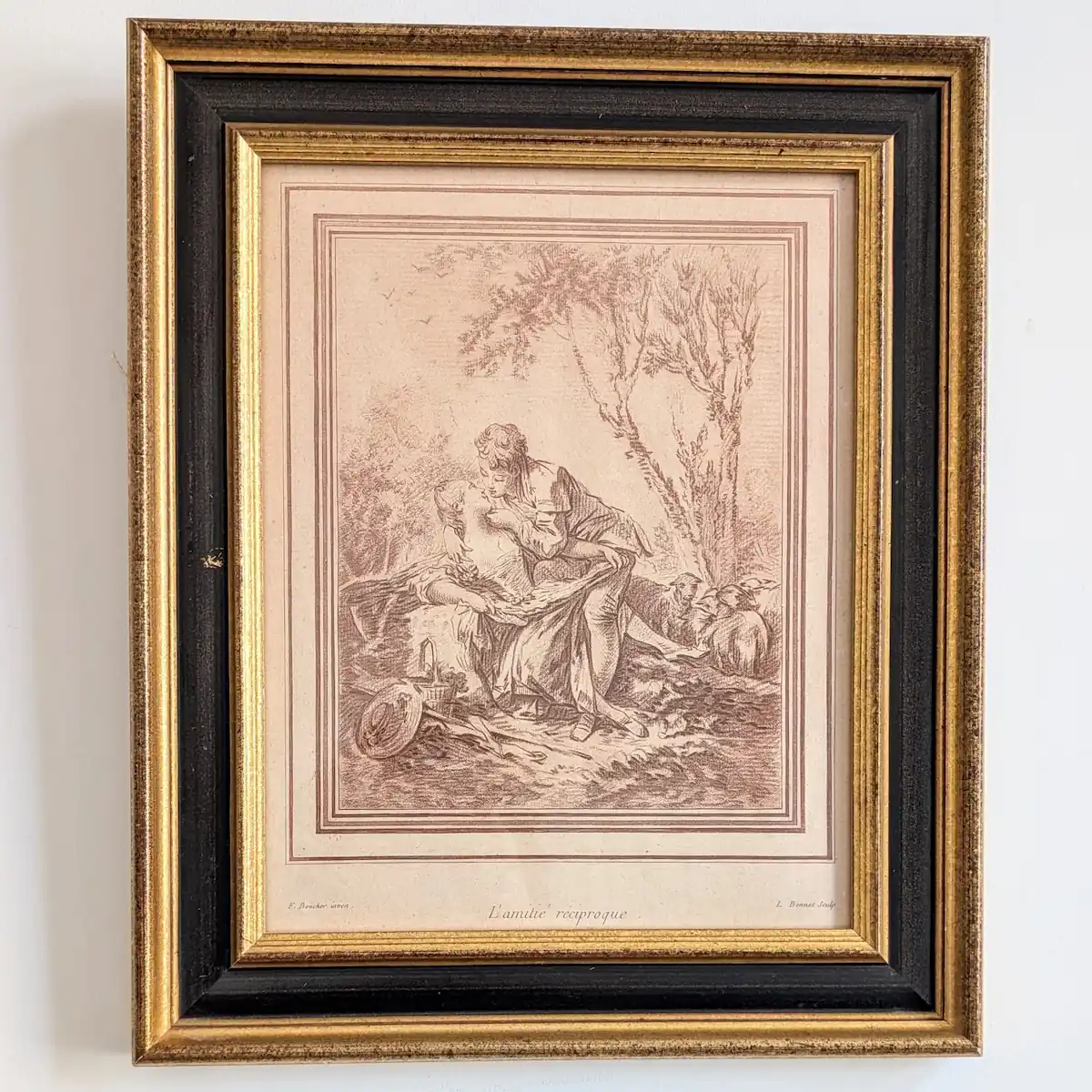 Gravure L’Amitié réciproque d’après Boucher, encadrée dans une baguette noire et dorée.