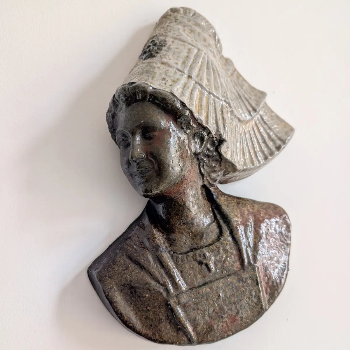 Buste mural de femme à coiffe ivoire évasée, au visage et au vêtement bruns