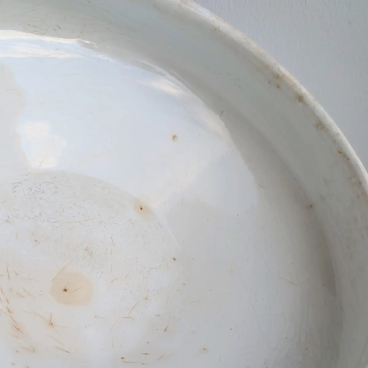 Intérieur blanc de soupière ancienne présentant de fines rayures, de petites taches et des marques d'usage.