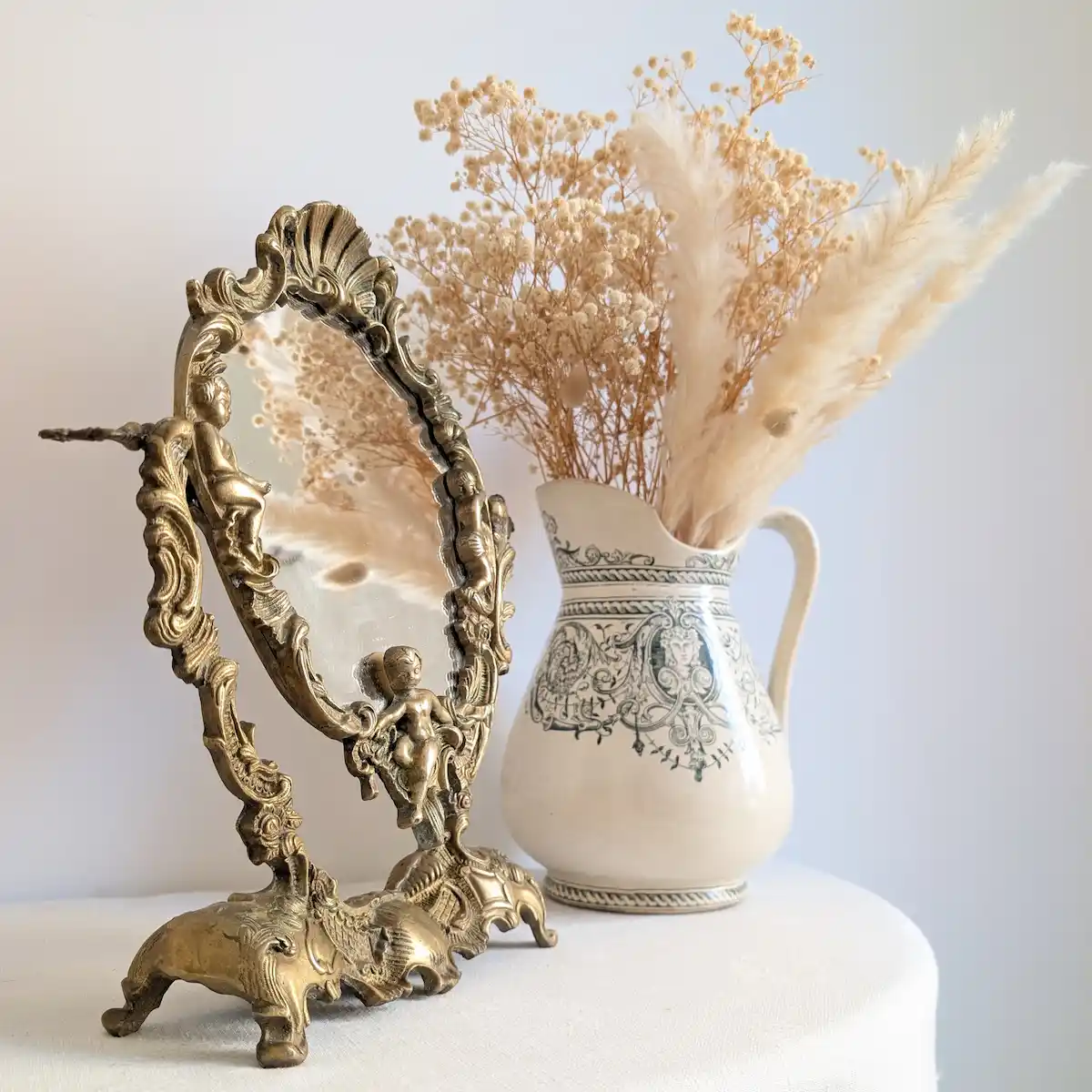 Pichet ancien en céramique à décor bleu garni de fleurs séchées, accompagné d'un miroir doré ornementé
