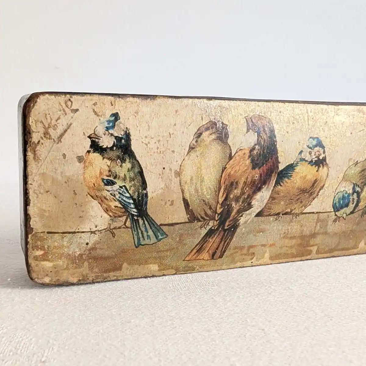 Détail de la partie gauche du couvercle, avec oiseaux polychromes, inscription peu lisible et pertes de décor.