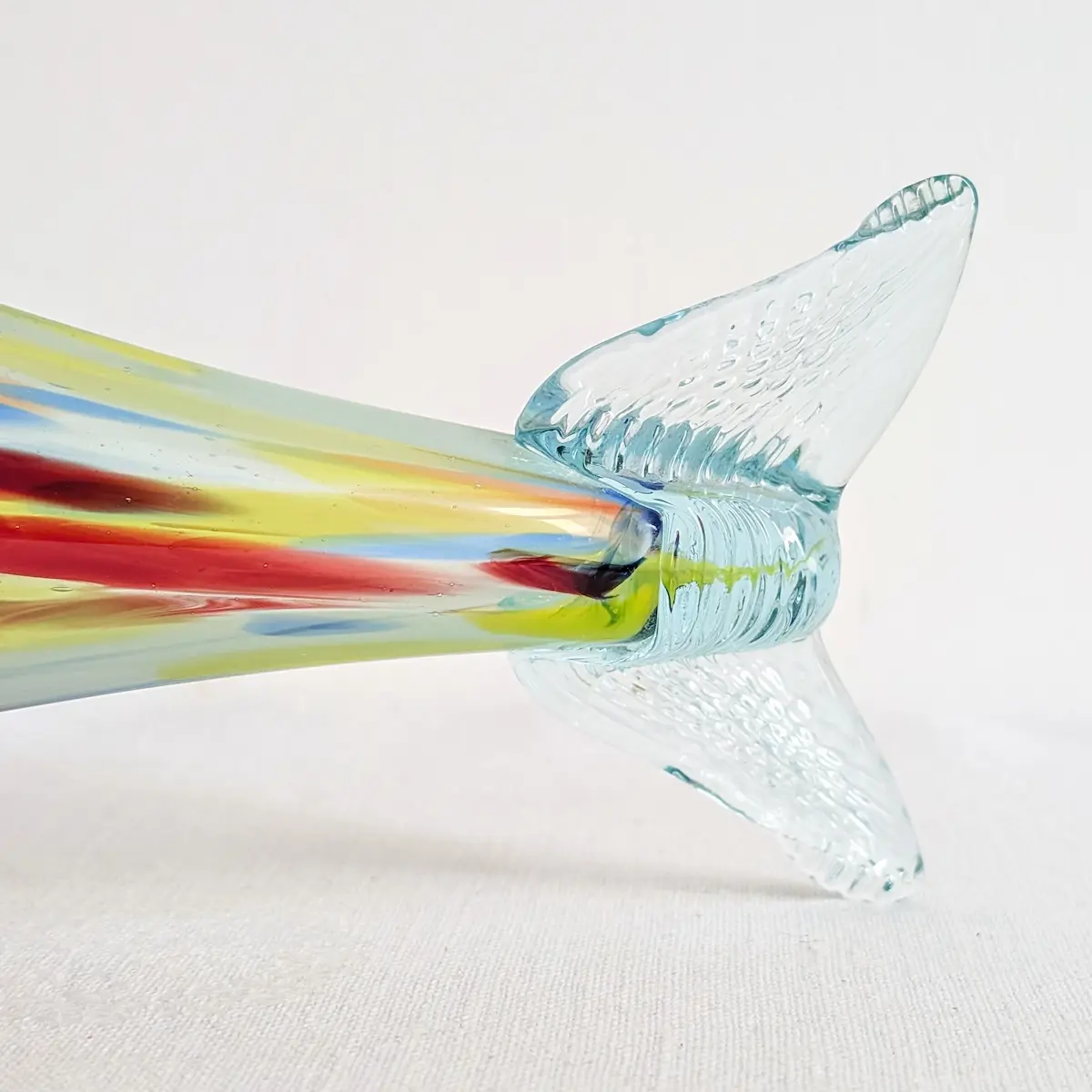 Détail de la queue bifide transparente et nervurée d'un poisson vintage en verre soufflé.