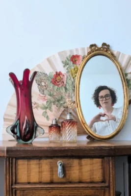Solenne Redon, fondatrice de Villa Brieg, dans le reflet d’un miroir ancien, parmi des objets de décoration vintage.