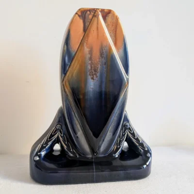 Vase en faïence bleu foncé et ocre vu de face, avec losange en relief et base ajourée.